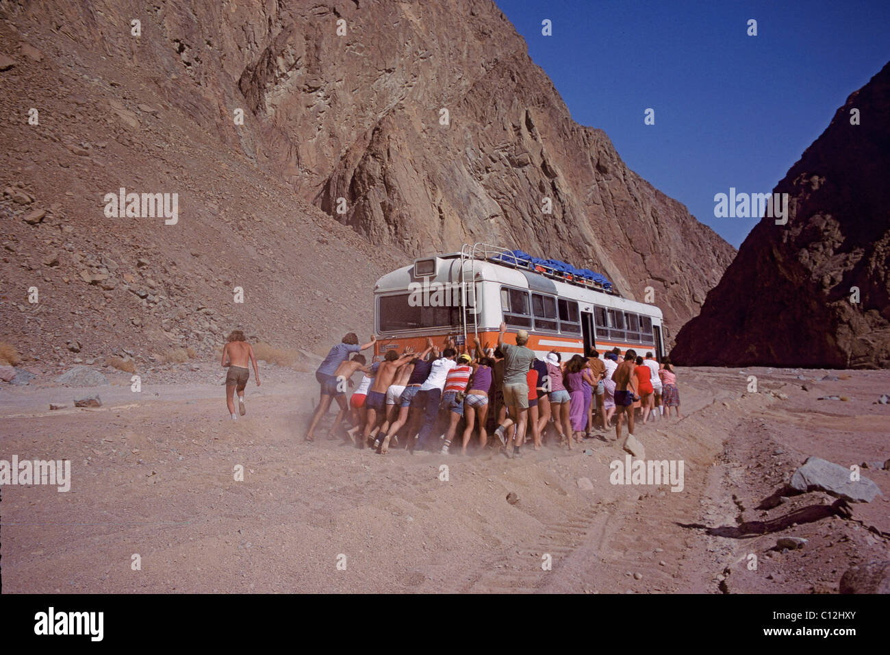 Passagiere, die schieben Bus durch Bergpass Stockfoto
