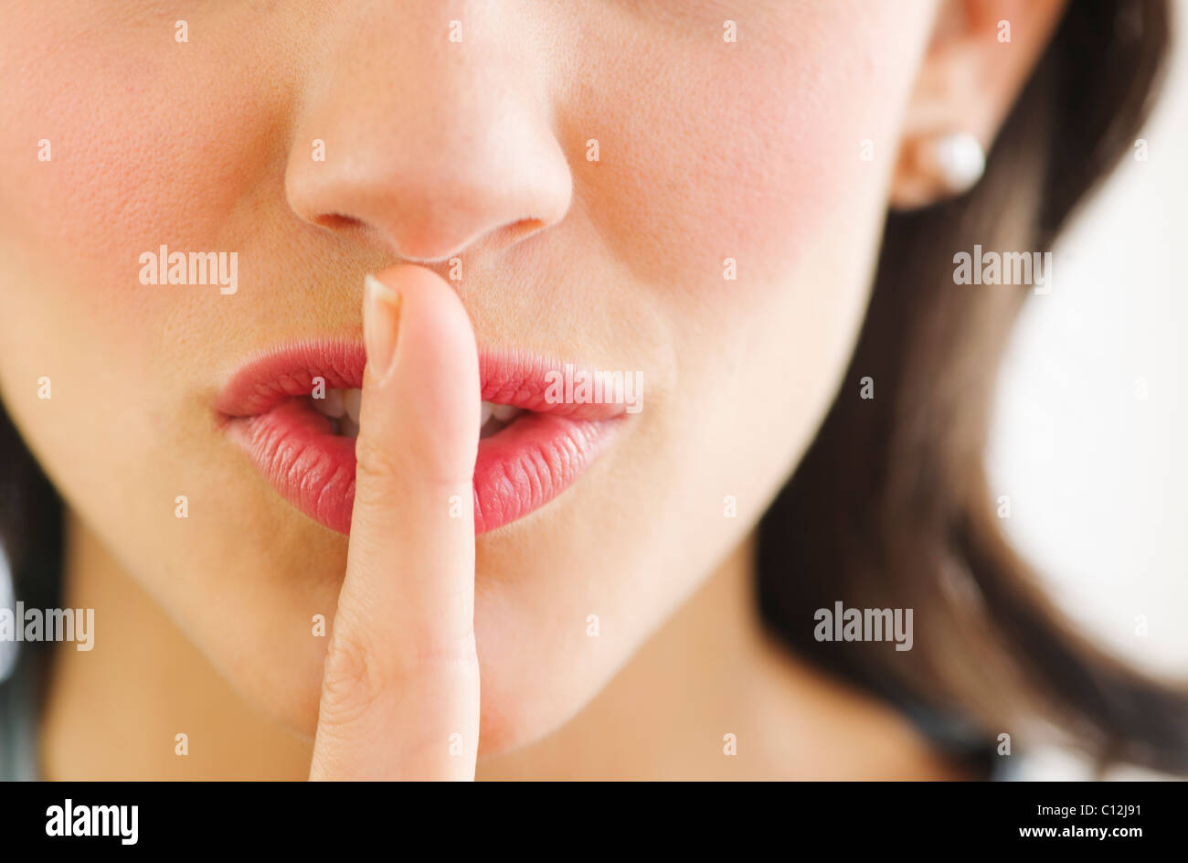 Junge Frau mit Finger auf Lippen, Nahaufnahme Stockfoto
