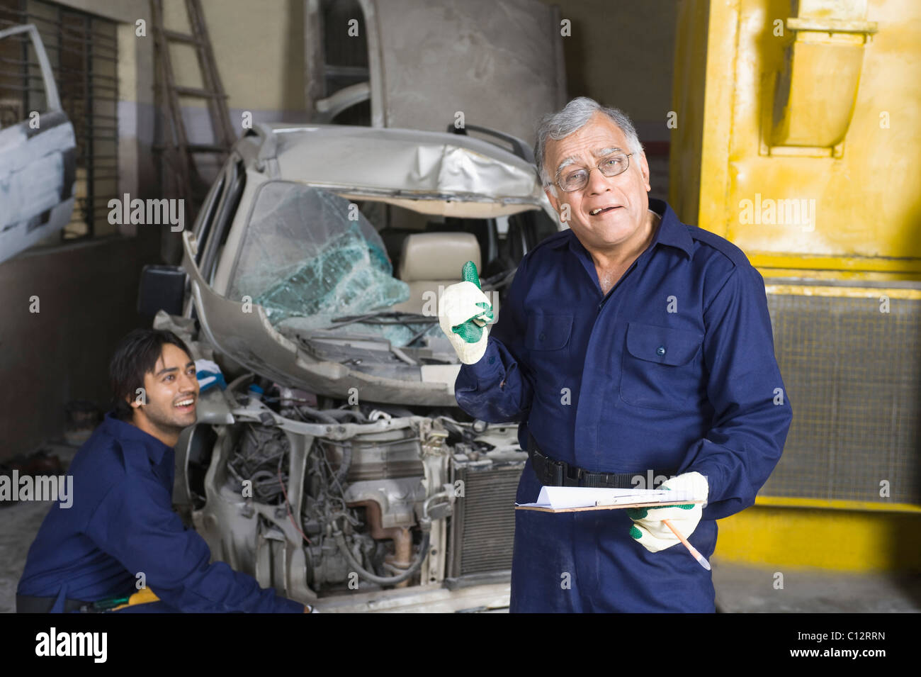 Porträt von Kfz-Mechaniker gestikulieren mit Lehrling reparieren ein Auto im Hintergrund Stockfoto