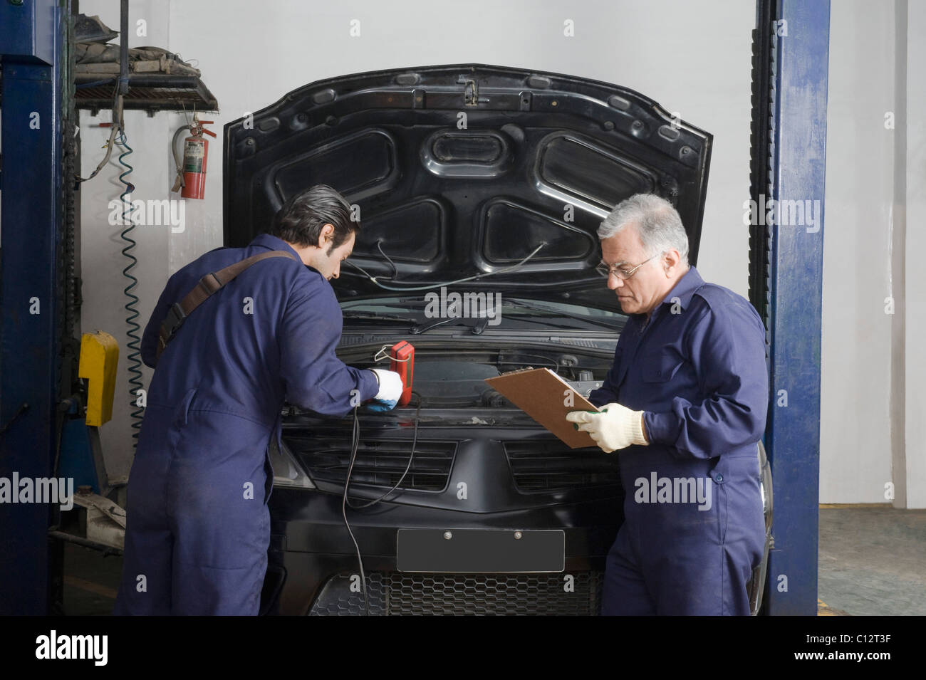 KfzMechaniker mit Lehrling ein Auto in einer Garage reparieren Stockfotografie Alamy