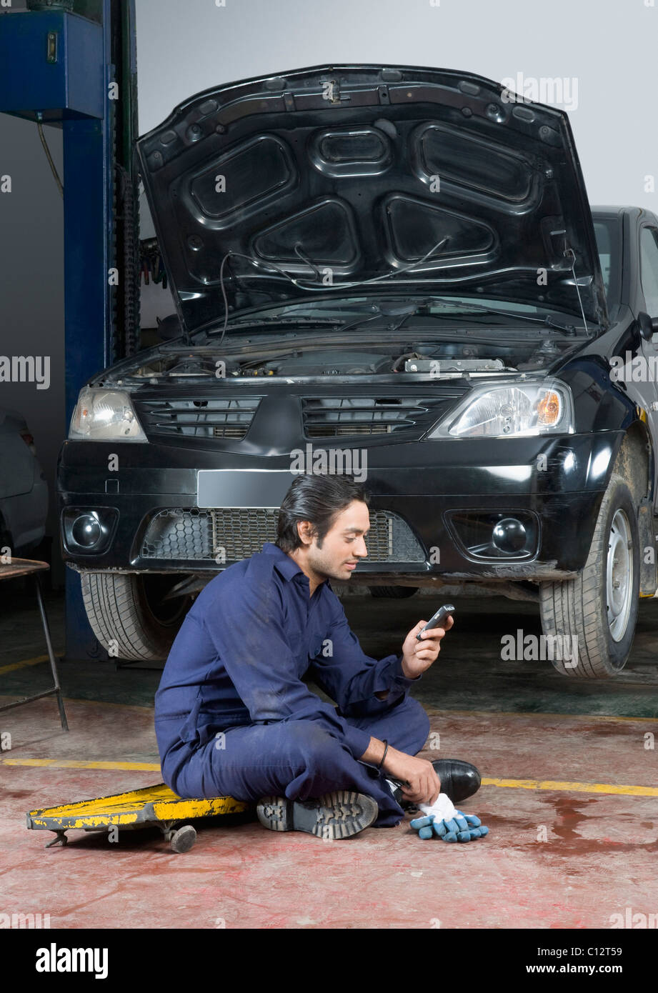 Kfz-Mechaniker mit einem Mobiltelefon in einer garage Stockfoto