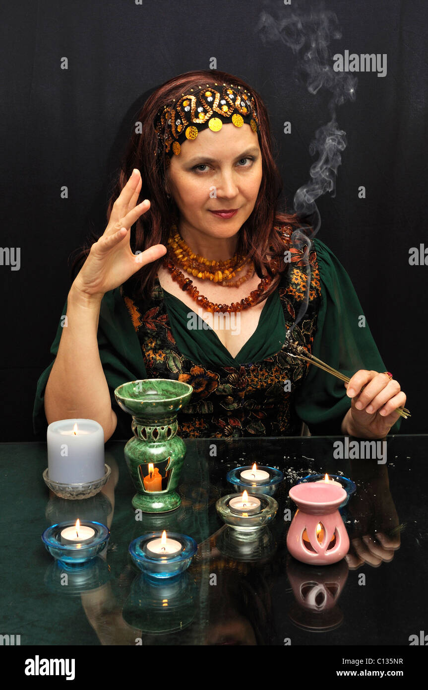 Magic Woman Rauchen Zweige auf schwarzem Hintergrund Stockfoto