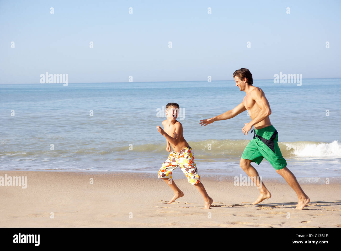 Vater jagt junge am Strand Stockfoto