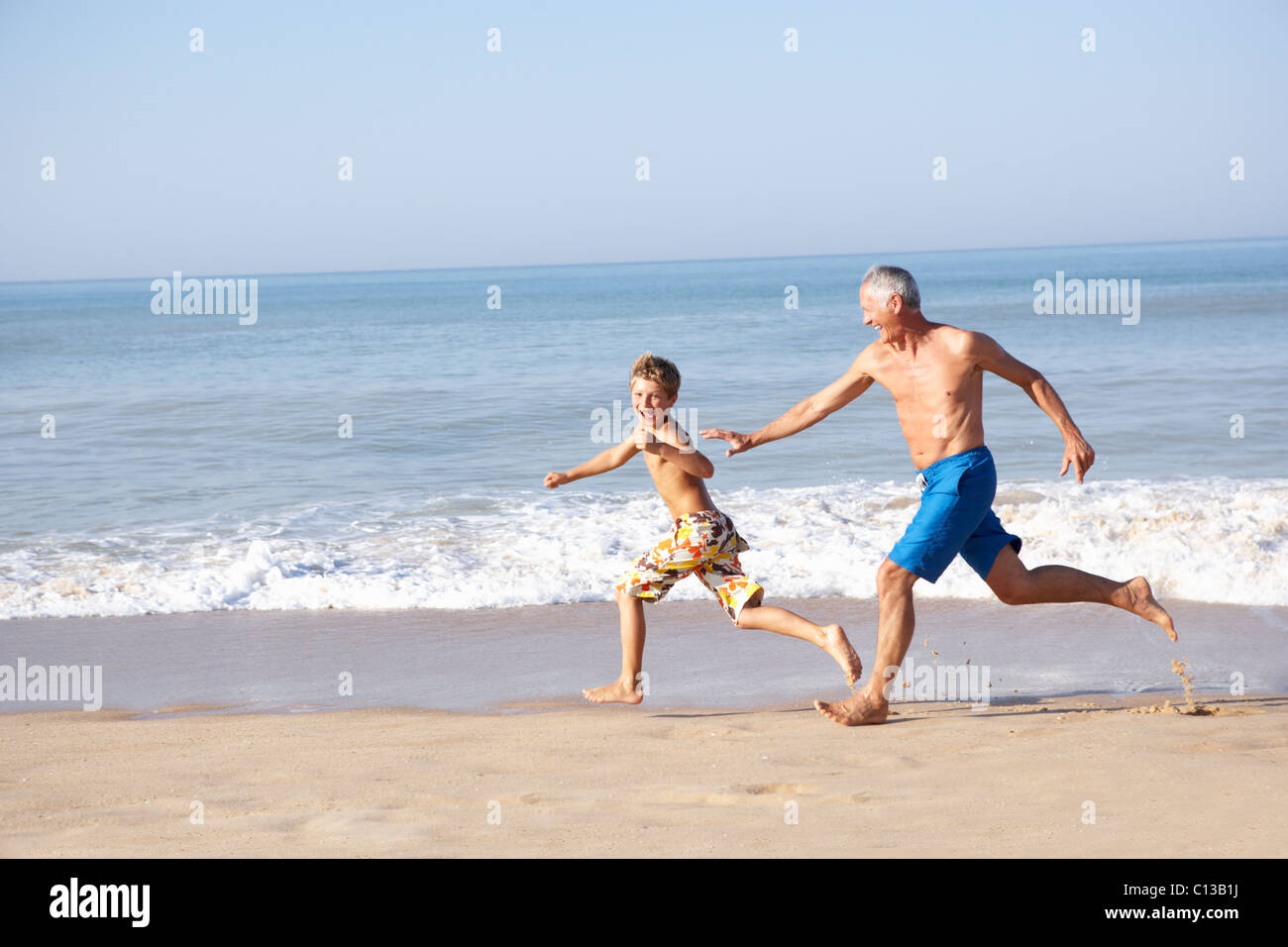 Großvater jagen junge am Strand Stockfoto