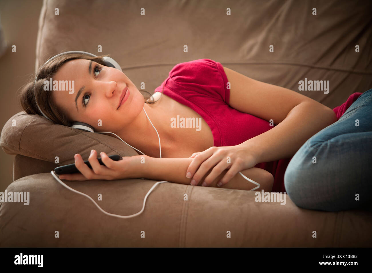 USA, Utah, Lehi, junge Frau auf dem Sofa liegend und Musik hören Stockfoto