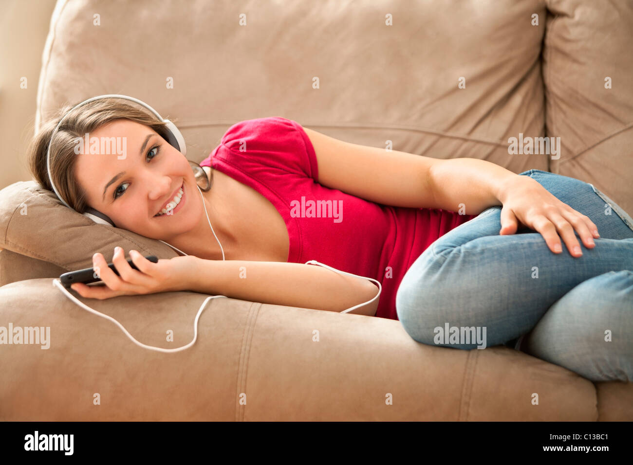 USA, Utah, Lehi, junge Frau auf dem Sofa liegend und Musik hören Stockfoto