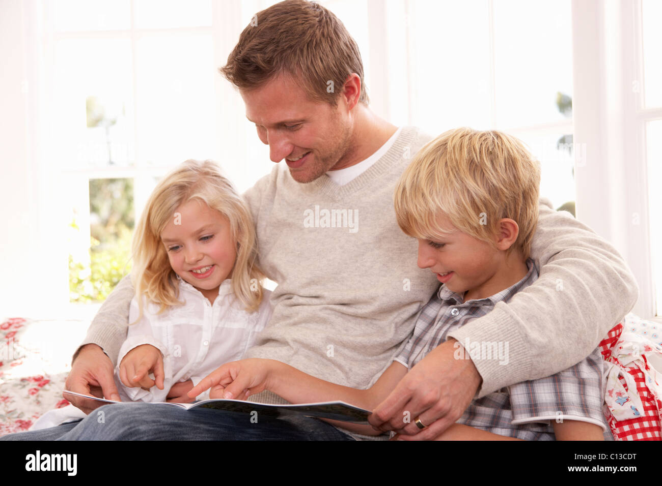 Mann und Kinder gemeinsam lesen Stockfoto