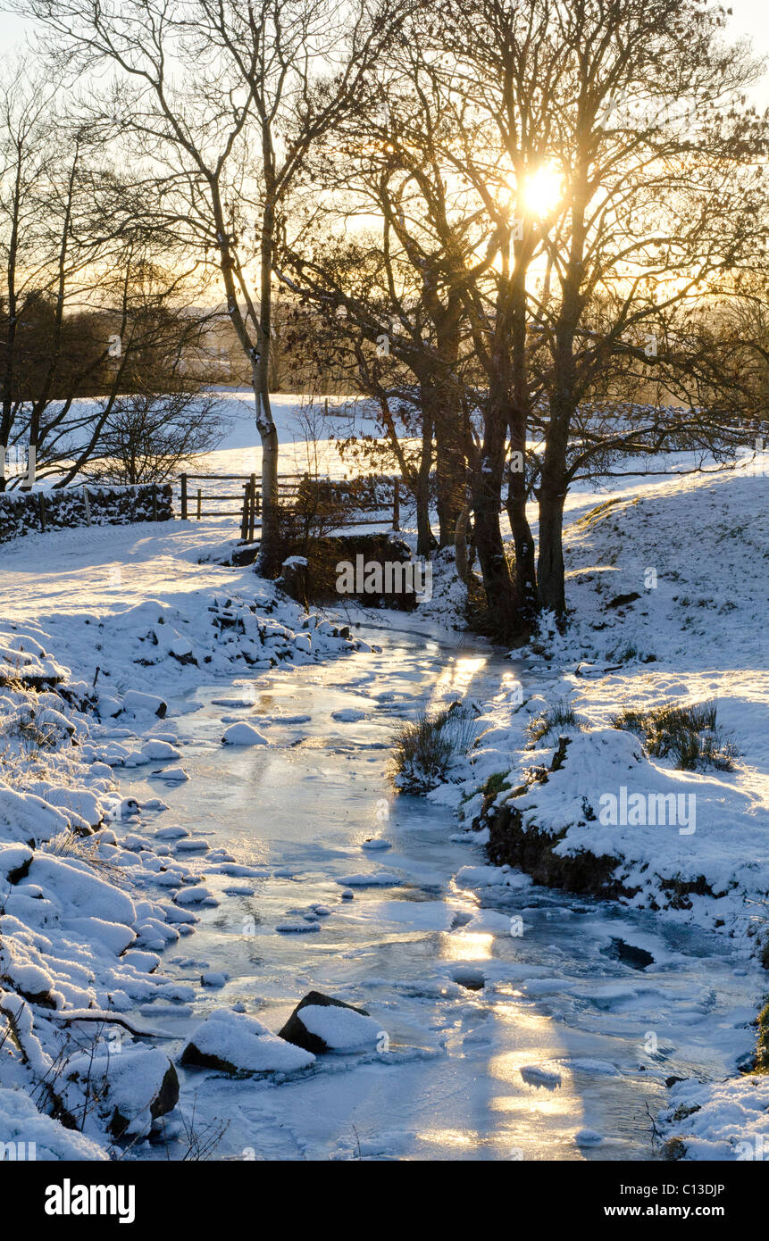 Kleiner Bach oder Verbrennung von Feld und Tor im tiefen Winter mit Sonnenuntergang Stockfoto