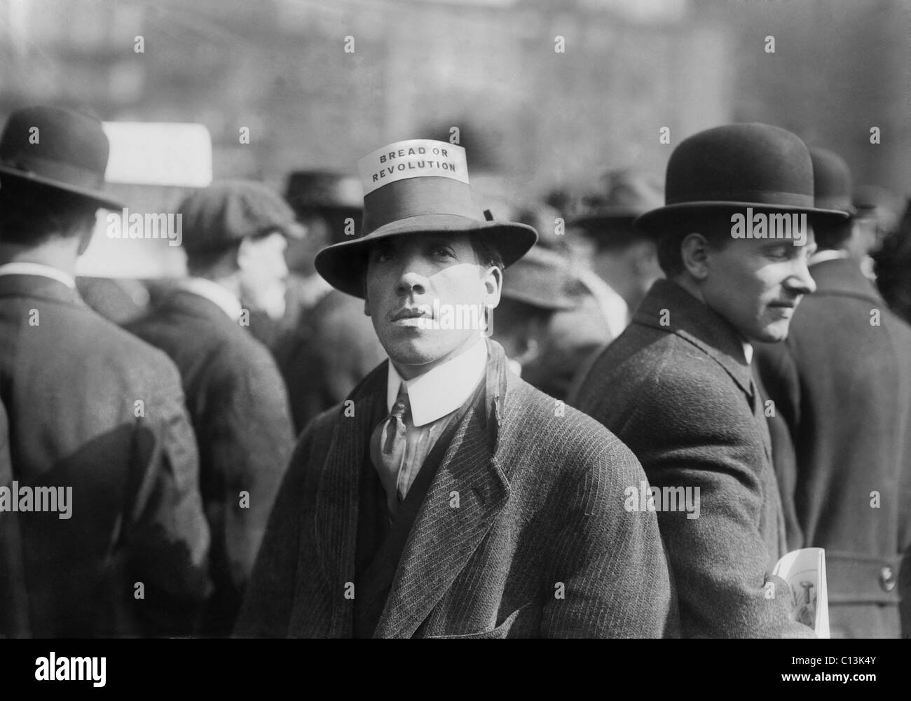 Mann trägt eine industrielle Arbeiter der Welt Hut Karte lesen "Brot oder Revolution" bei einer Kundgebung am New Yorker Union Square. Ca. 1914. Stockfoto