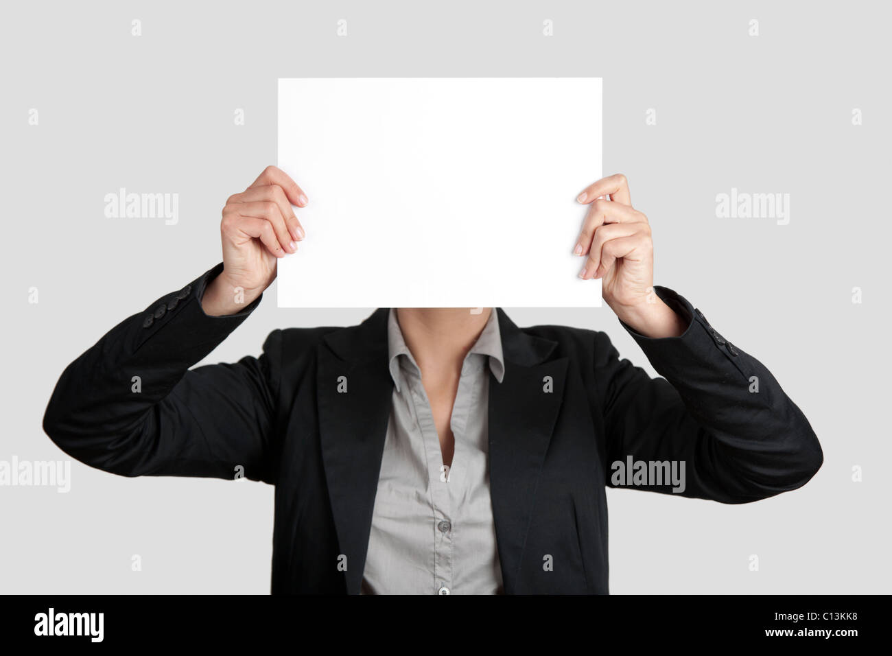 Frau zeigt ein leeres Blatt Papierblatt vor dem Kopf Stockfoto