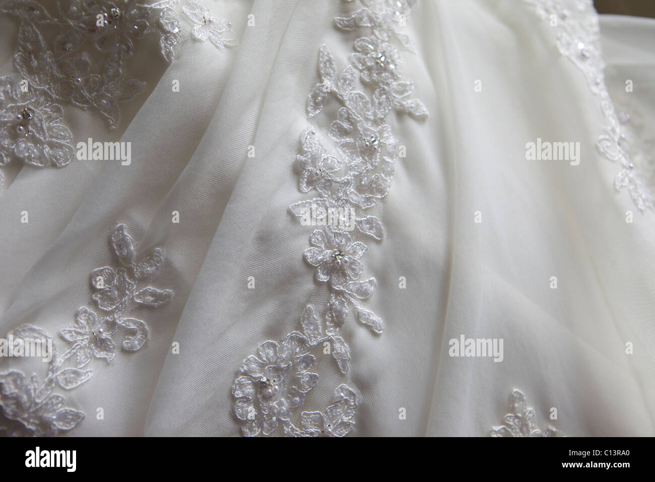 Eine Nahaufnahme von einem Hochzeitskleid zeigt die Details der Blumen. Stockfoto