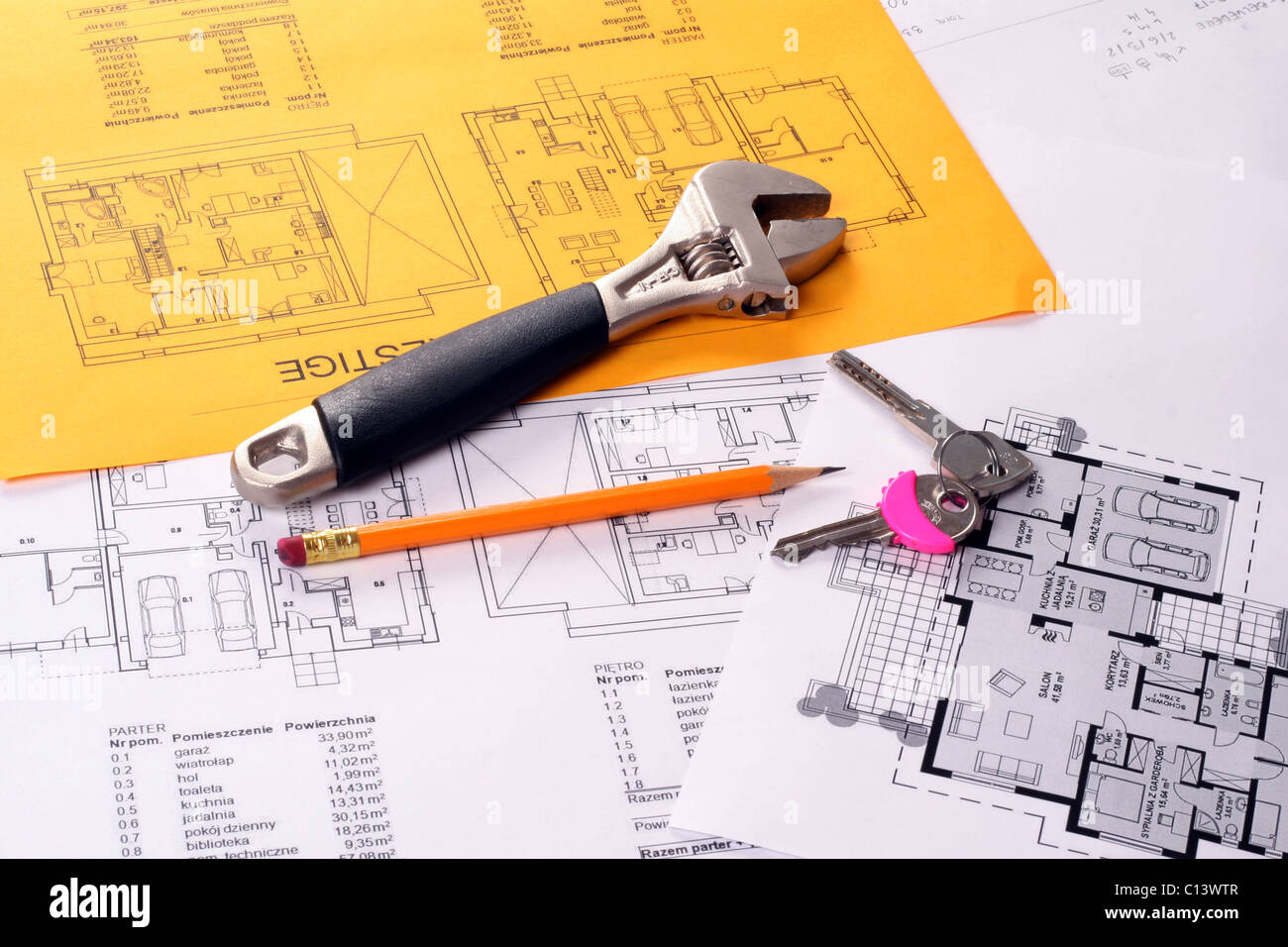 Werkzeuge wie Schraubenschlüssel, Schlüssel und Bleistift Hauspläne Baupläne auf weißen und gelben Papier gedruckt Stockfoto
