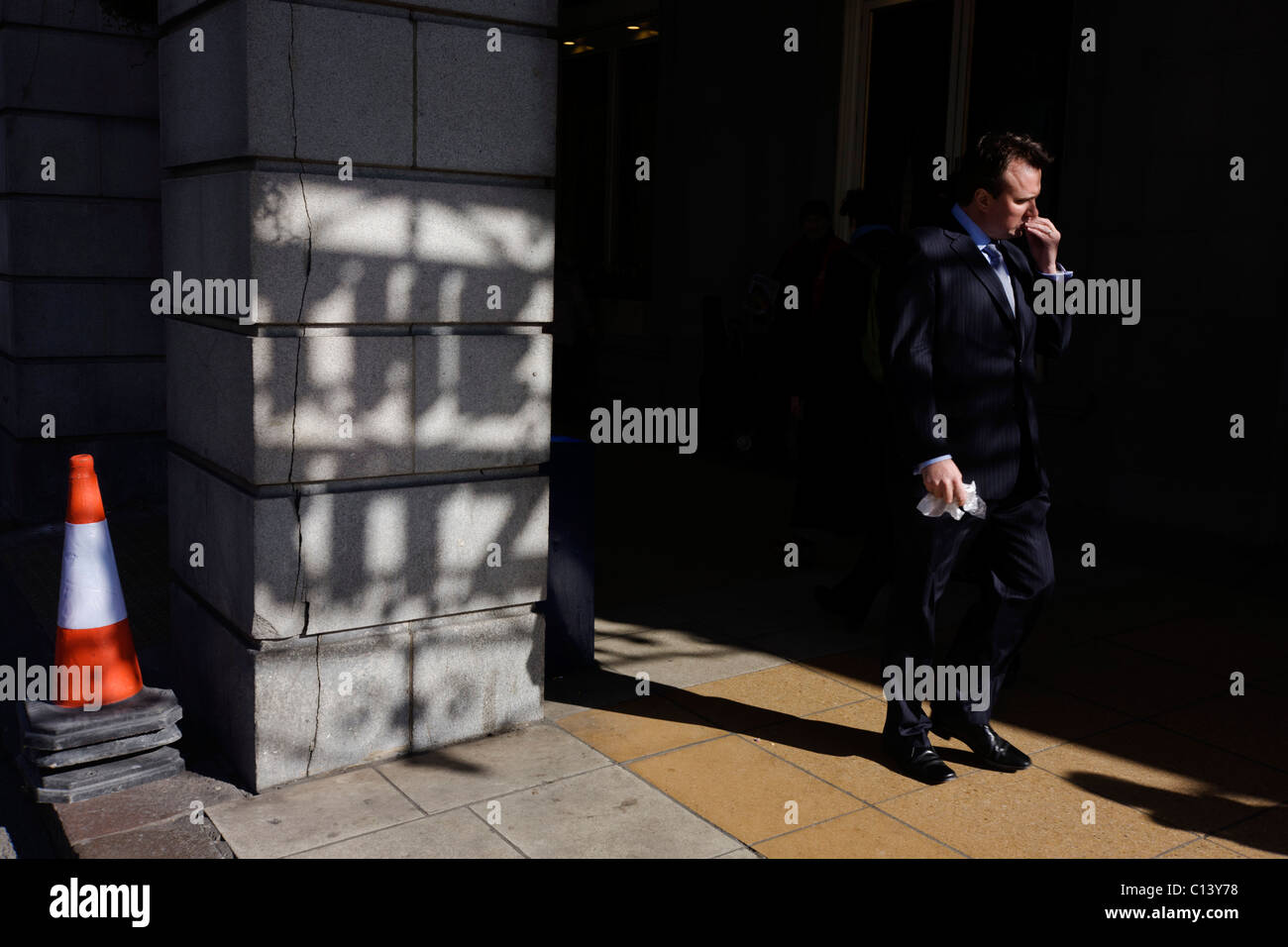 Mittags Passant geht vorbei an einen Schatten des Zeichens Ritz Hotel, zeigt auf einer Säule vor dem berühmten Londoner Wahrzeichen. Stockfoto