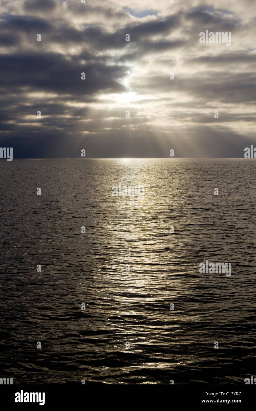 Strahlen der Sonne beleuchten die Oberfläche des offenen Meeres. Stockfoto