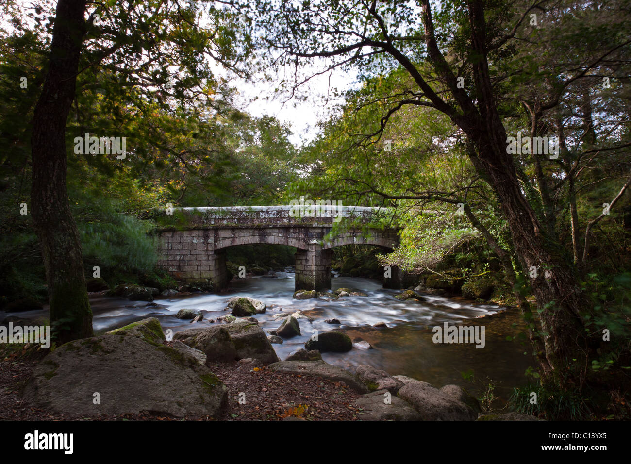 Alte Steinbrücke überquert einen Fluss auf Dartmoor. Stockfoto