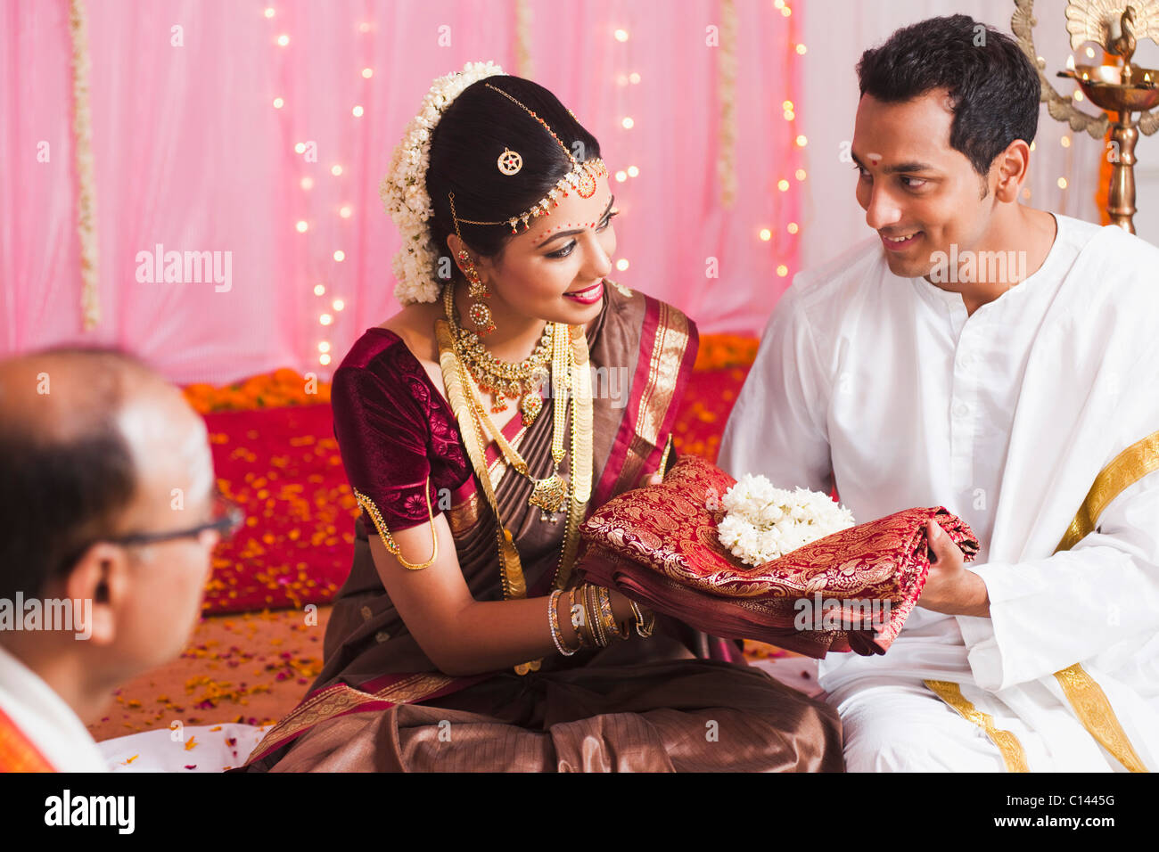 Bräutigam der Braut bei der Süd-indischen Hochzeit Zeremonie einen Sari verleihen Stockfoto