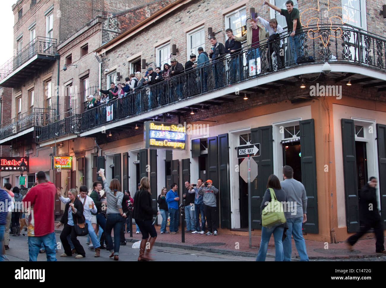 Menschen trinken und tanzen auf der Straße als Leute zu beobachten auf dem Balkon einer Bourbon Street Bar in New Orleans Stockfoto