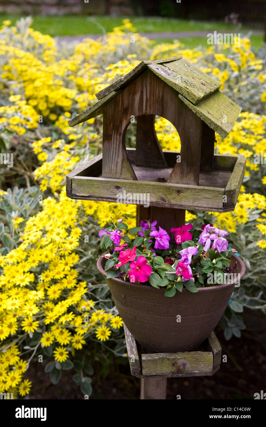 Blumen und ein Vogelhaus in einem englischen Landhaus-Garten Stockfoto