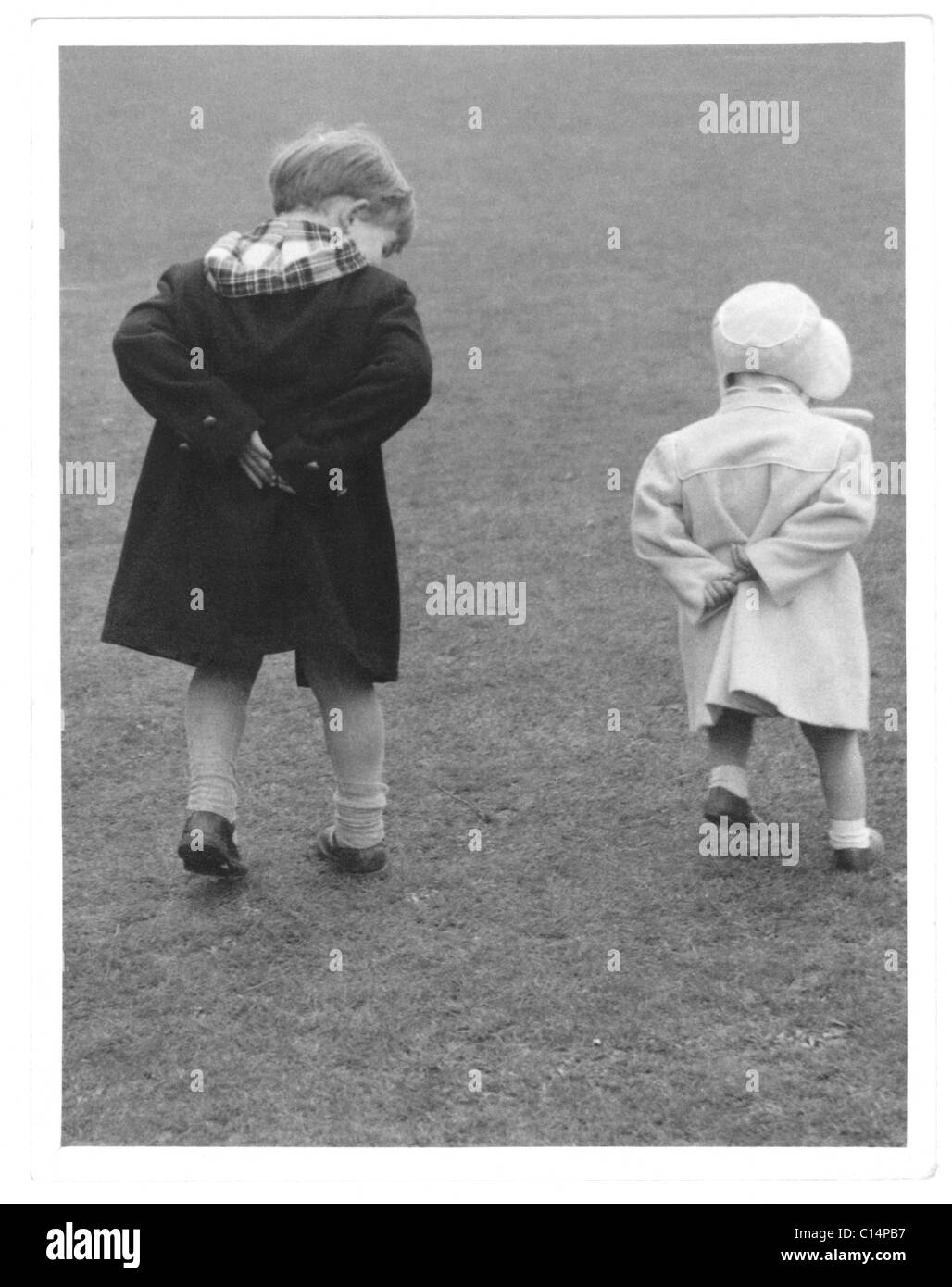 Original-charmantes Foto von zwei süßen kleinen Kindern, möglicherweise älterer Bruder mit jüngerer Schwester, die beide mit den Händen hinter dem Rücken laufen - um die 1950er Jahre, Großbritannien Stockfoto