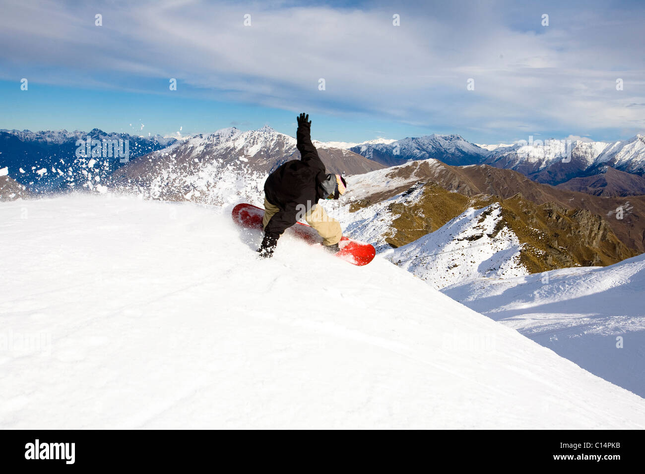 Eine männliche Snowboarder sprengt eine Ferse Seite Wende beim Snowboarden in Coronet Peak in Queenstown, Neuseeland. Stockfoto