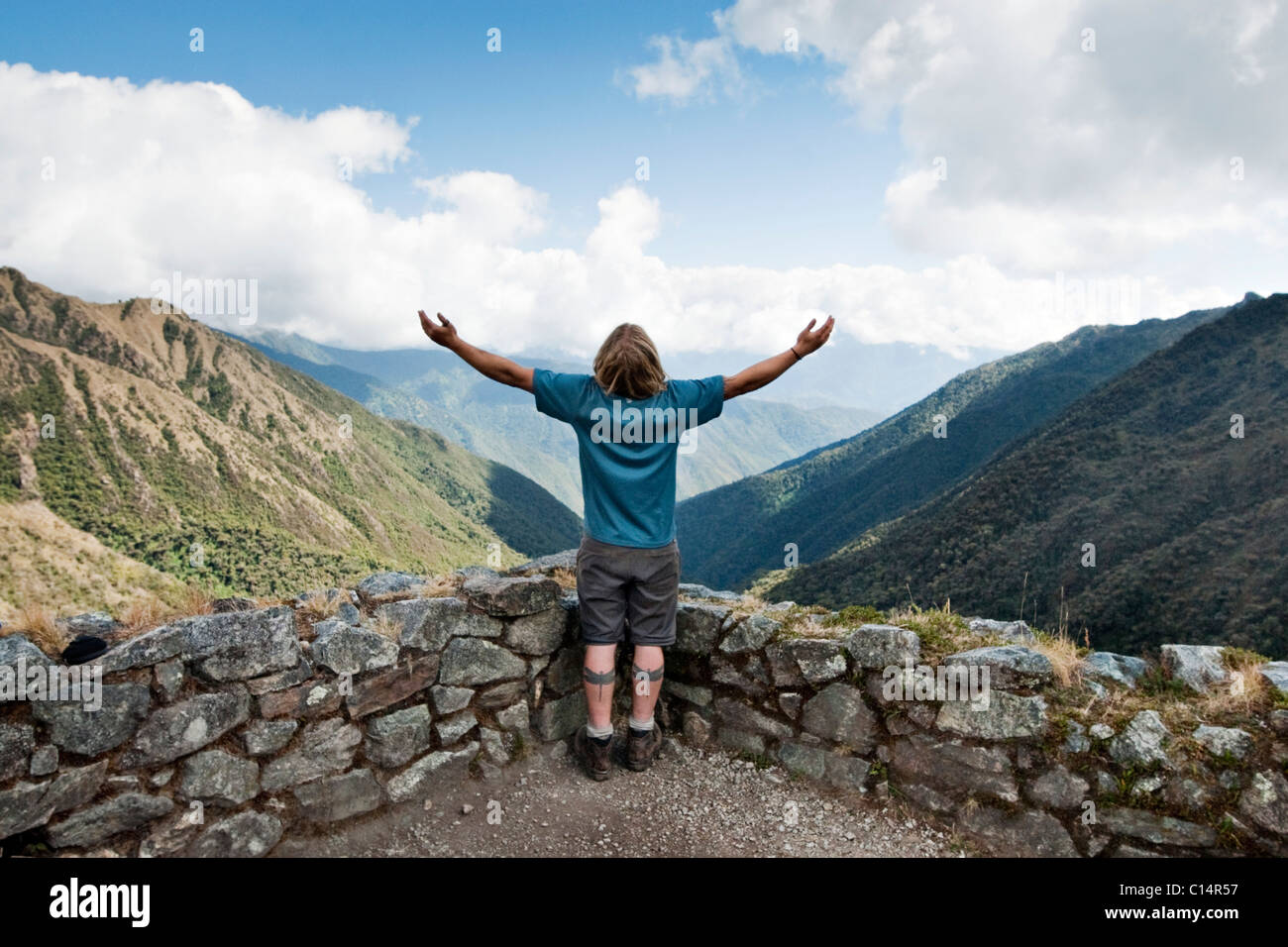 Ein junger Mann breitet seine Arme in die Landschaft in den Anden entlang des Inka-Trail zu. Stockfoto