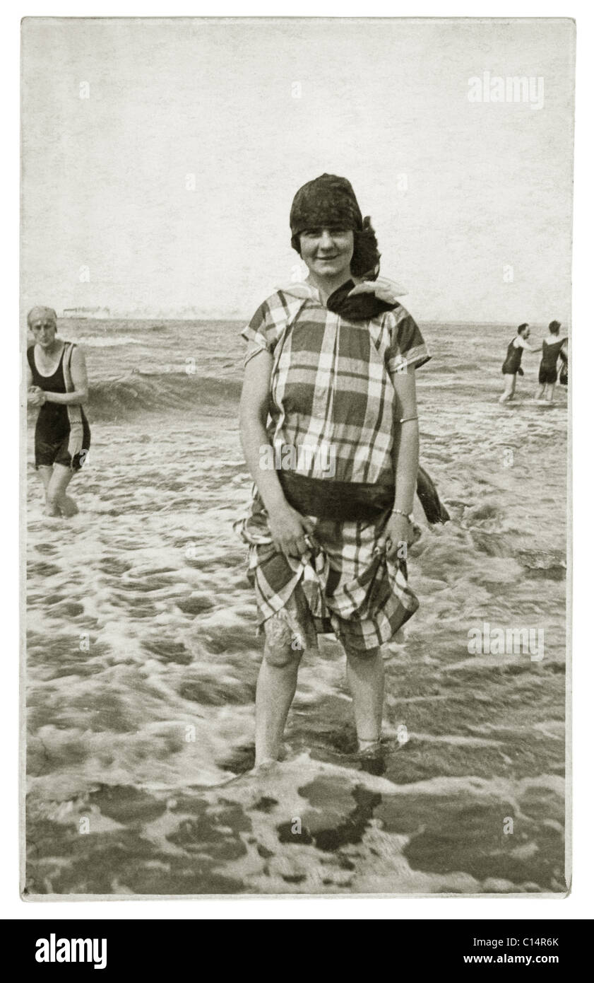 Ursprüngliche Postkarte aus der Zeit der 1920er Jahre mit einer jungen Frau in Freizeitkleidung, die im Meer paddelt - Zeitvertreibe Anfang der 1920er Jahre, britisches Retro-Strandfoto. Stockfoto