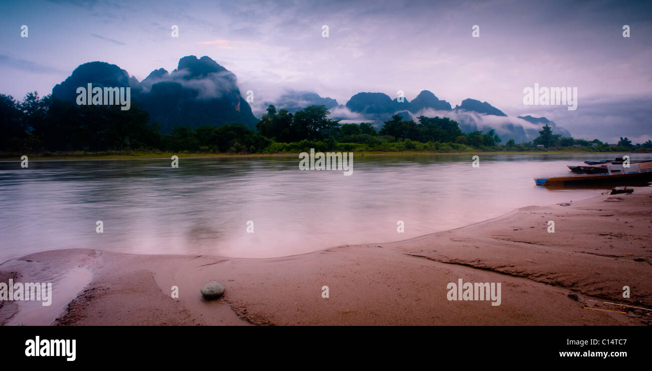 Kleiner Stein, Fluss und die Berge in Nebel bedeckt.  Vang Vieng, Laos, Asien. Stockfoto