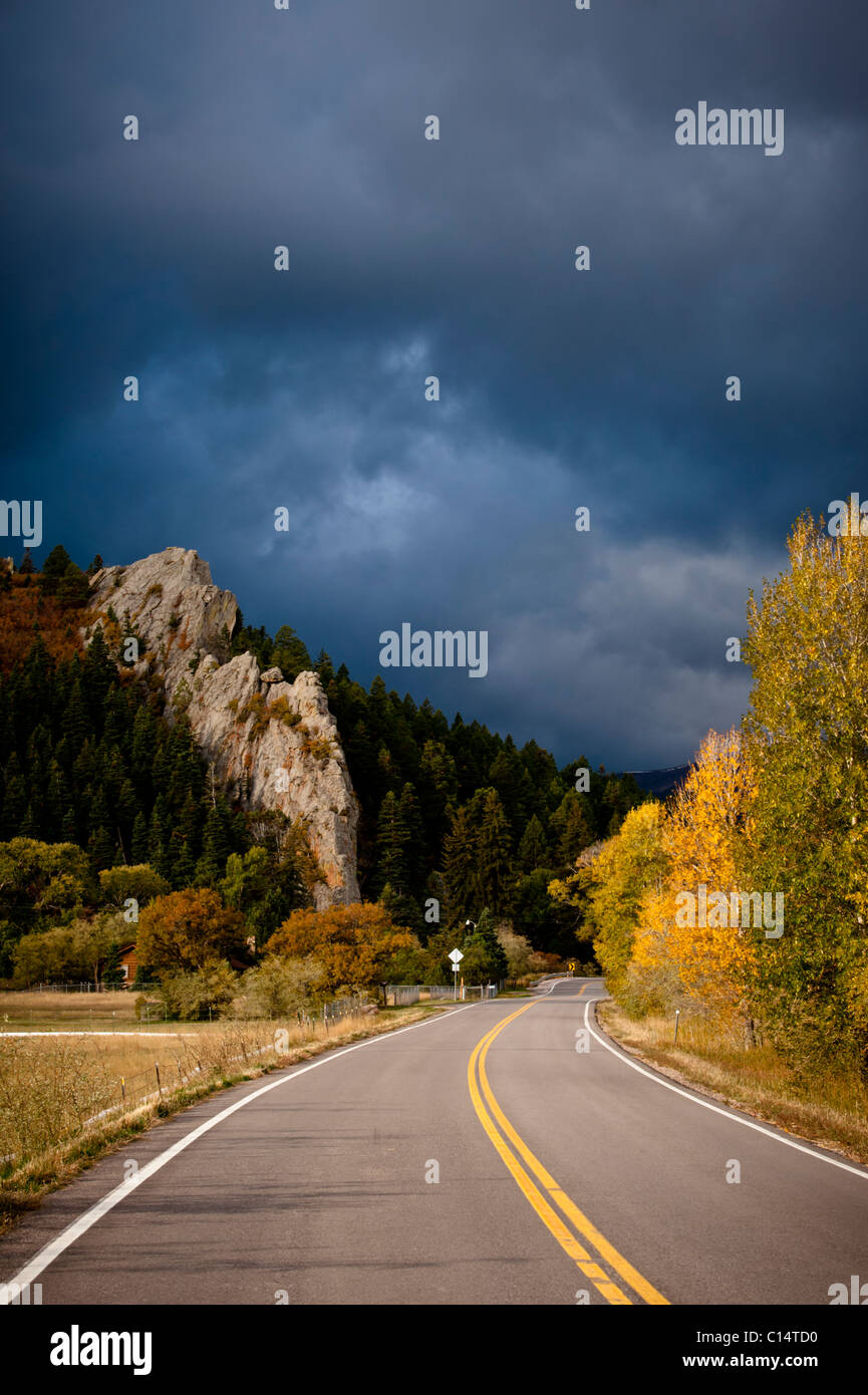 Autobahn mit Bäumen in Herbstfarben und stürmischen Himmel.  Walsenburg, Colorado. Stockfoto