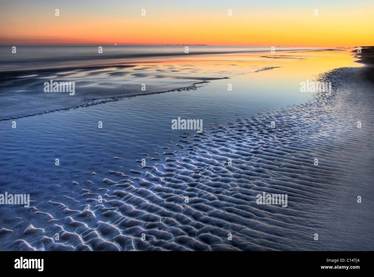 Ein Sonnenuntergang spiegelt sich bei Ebbe am Strand Coligny auf Hilton Head Island, South Carolina. Stockfoto