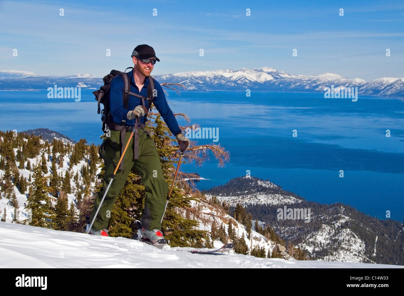 Eine männliche Skifahrer Skins oben Mount Tallac mit Lake Tahoe im Hintergrund, CA. Stockfoto