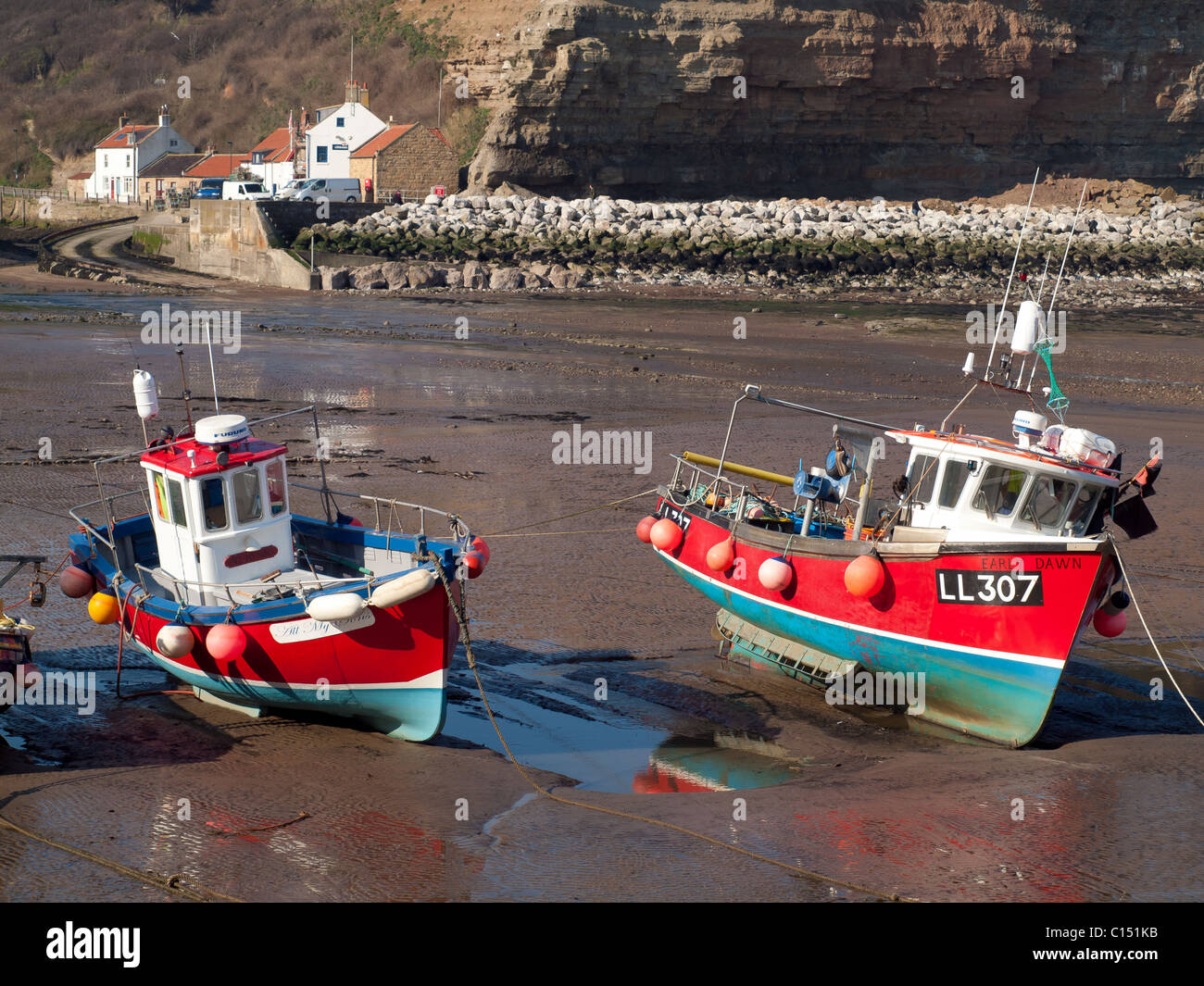 Flut, Staithes Hafen an einem sonnigen Frühlingsmorgen mit leuchtend roten gemalt Angelboote/Fischerboote liegen auf dem nassen sand Stockfoto