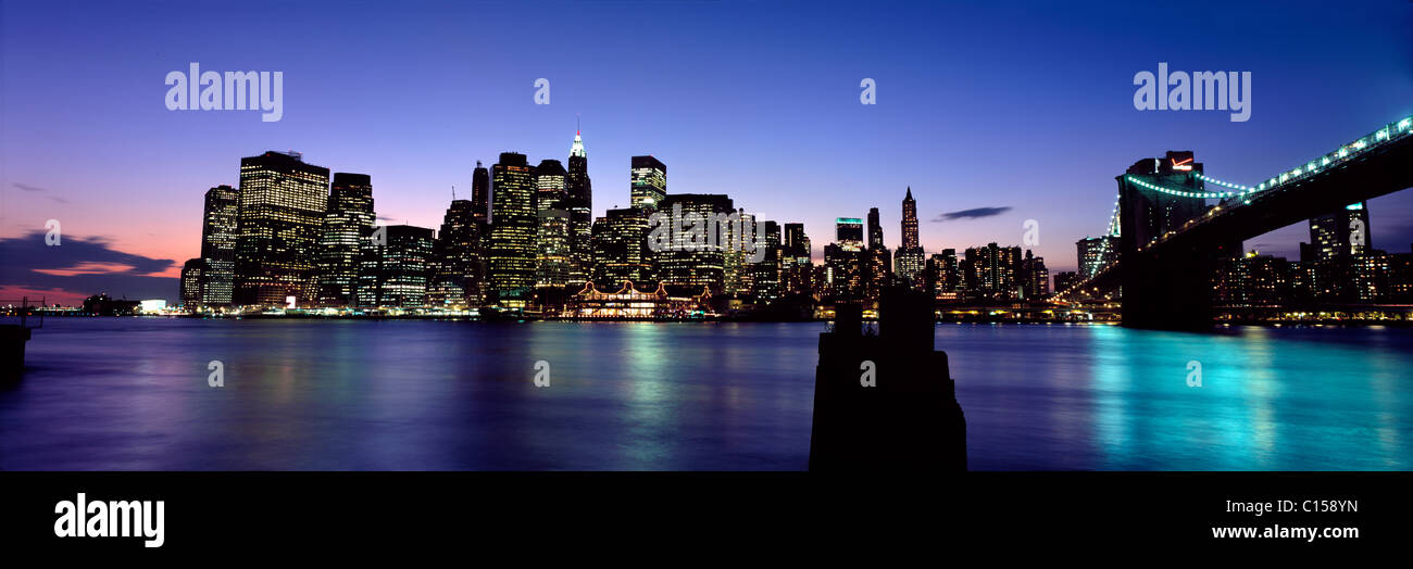Lower Manhattan und Brooklyn Bridge beleuchtet in der Abenddämmerung Stockfoto