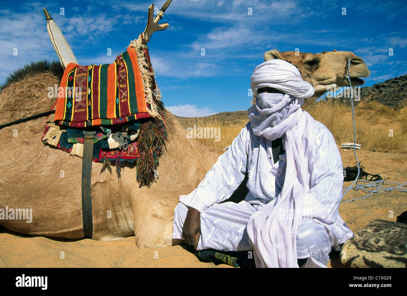 Tuareg Mann sitzt neben seinem Kamel, Libyen, Nordafrika Stockfoto