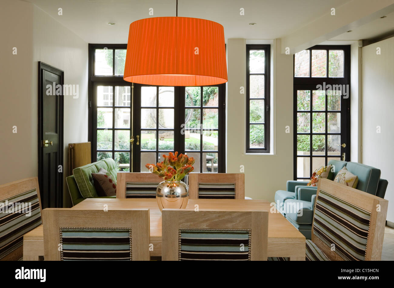 Große orange Lampenschirm über dem Esstisch aus Holz im Zimmer mit Glas verkleidet windows Stockfoto