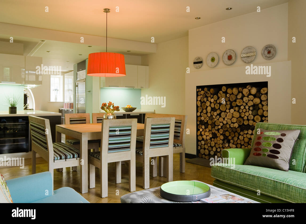 Große orange Lampenschirm über dem Esstisch in offene Küche Zimmer mit Brennholz Stockfoto