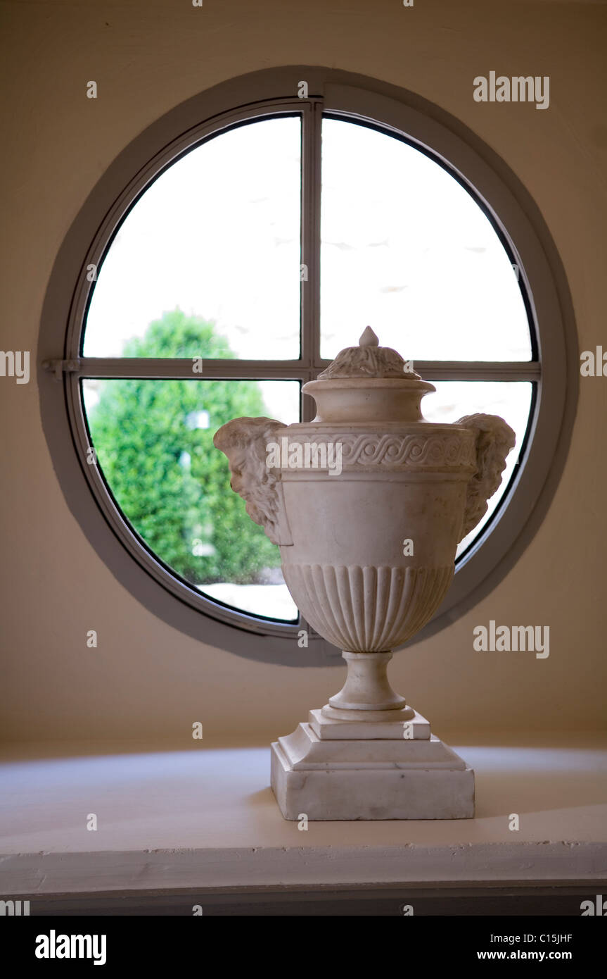 Klassische griechische Urne auf dem Sims ein rundes Fenster Stockfoto