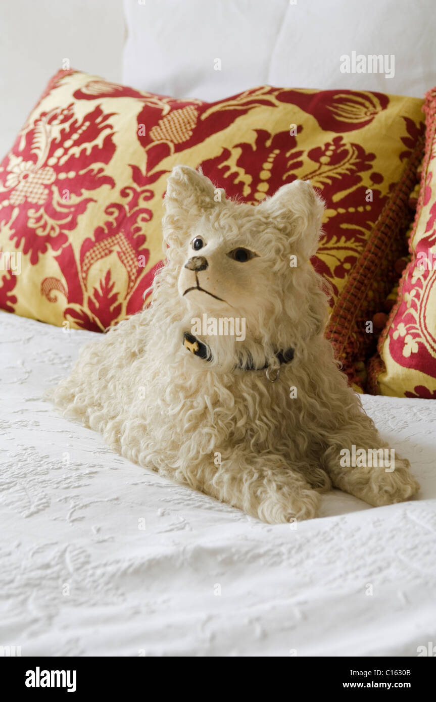 Kuscheliges Hundespielzeug auf weiße Bettwäsche mit barocken gemusterten Kissen Stockfoto