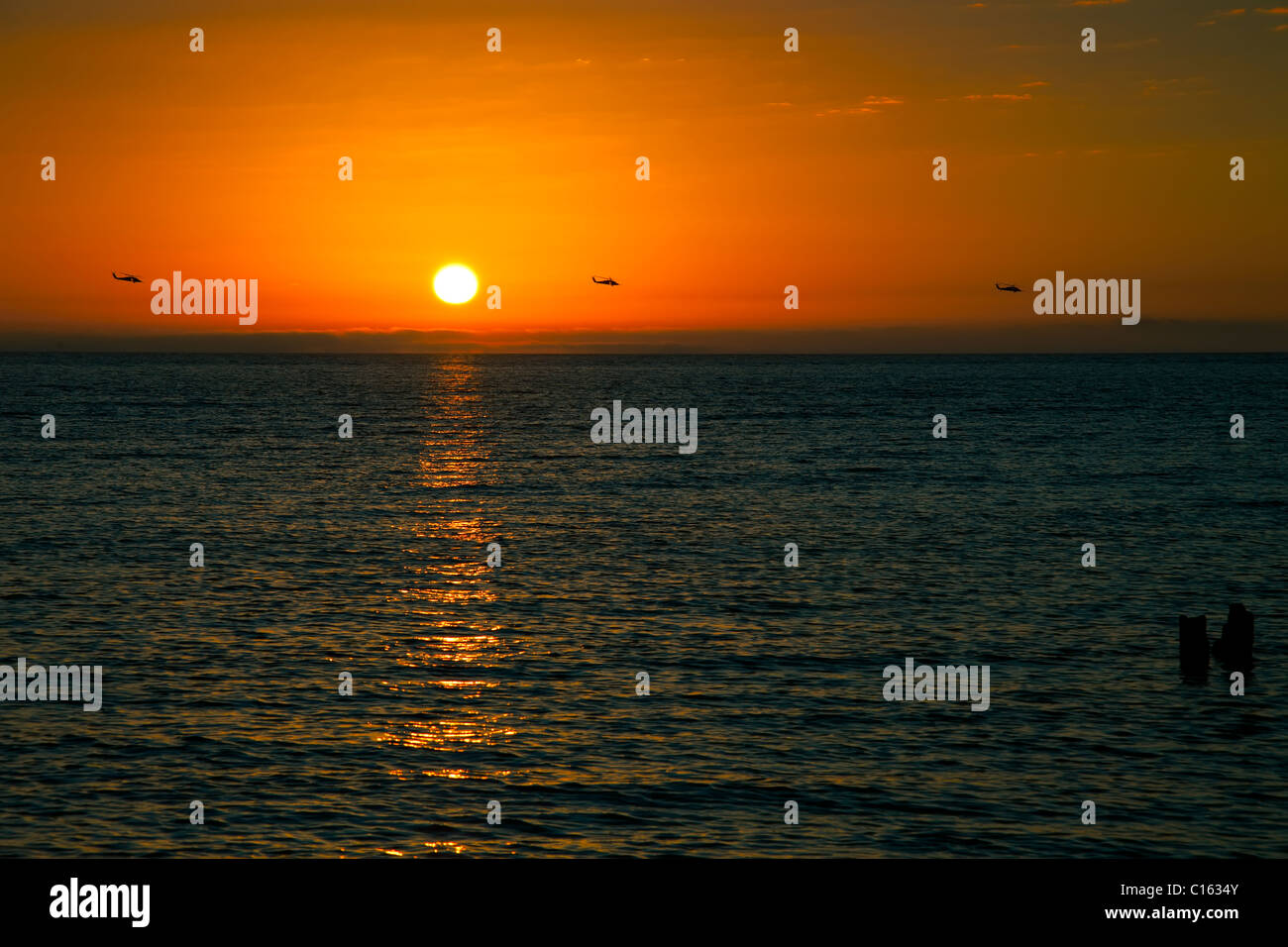 Drei Militärhubschrauber Überführung im Golf von Mexiko bei Sonnenuntergang Stockfoto