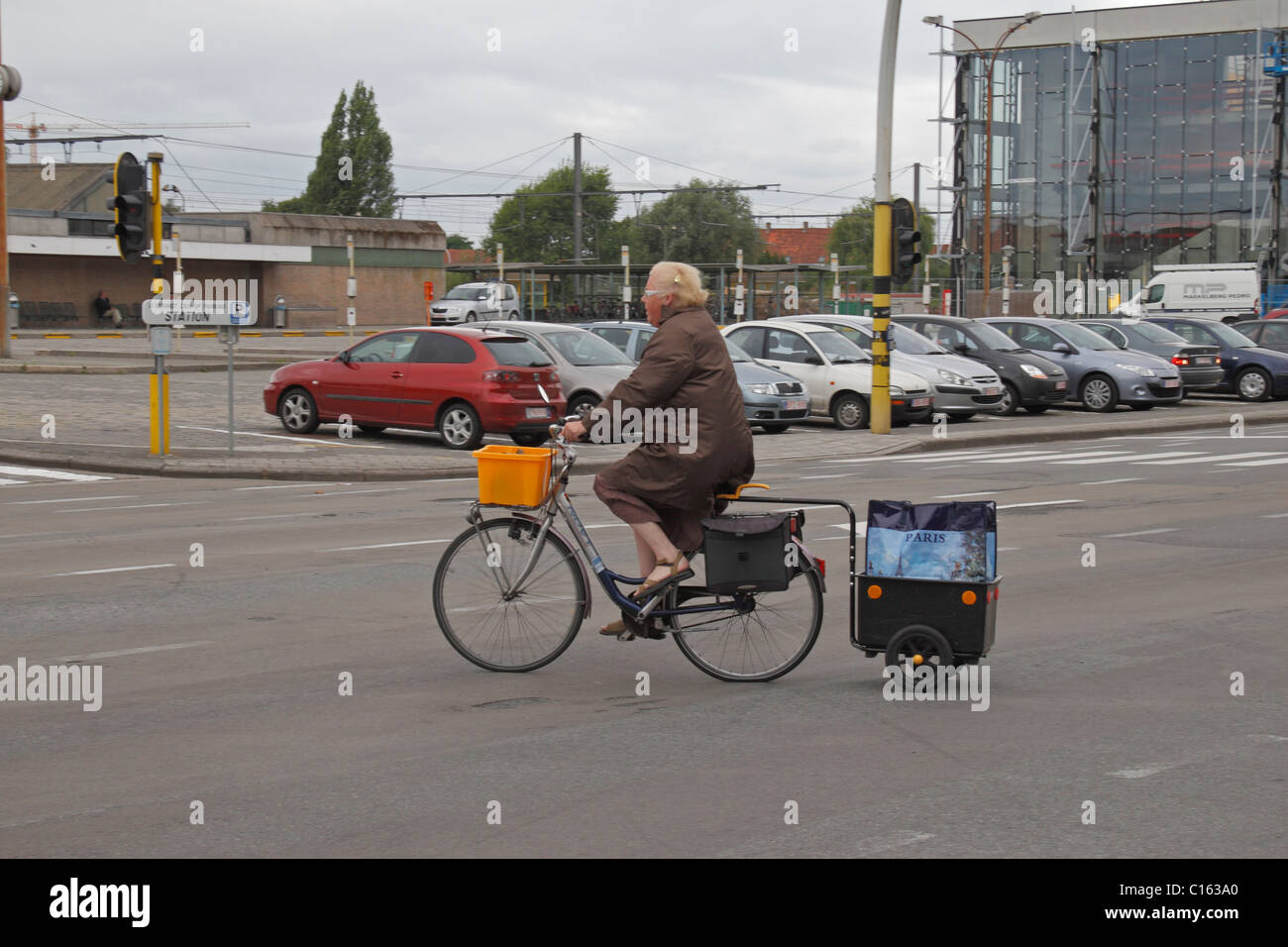 Frau auf Bicycycle ziehen einen kleinen Anhänger in einer Straßenkreuzung am Rande des Ieper (Ypern), Belgien. Stockfoto