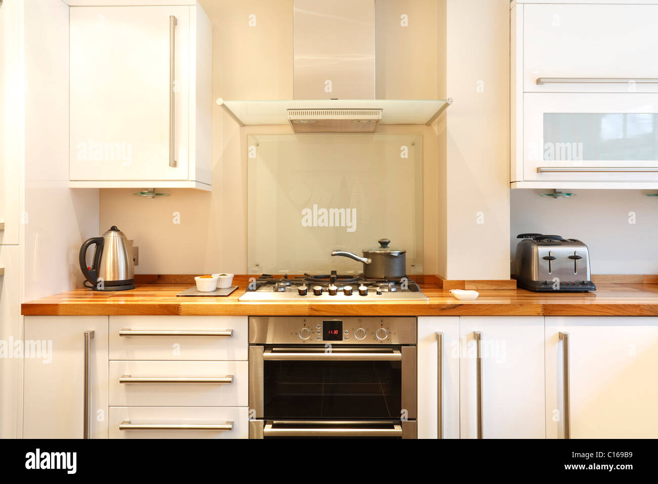 Moderne Küche mit Gas-Kochfeld, Dunstesse, Holz Arbeitsplatten und Geräten aus rostfreiem Stahl Stockfoto