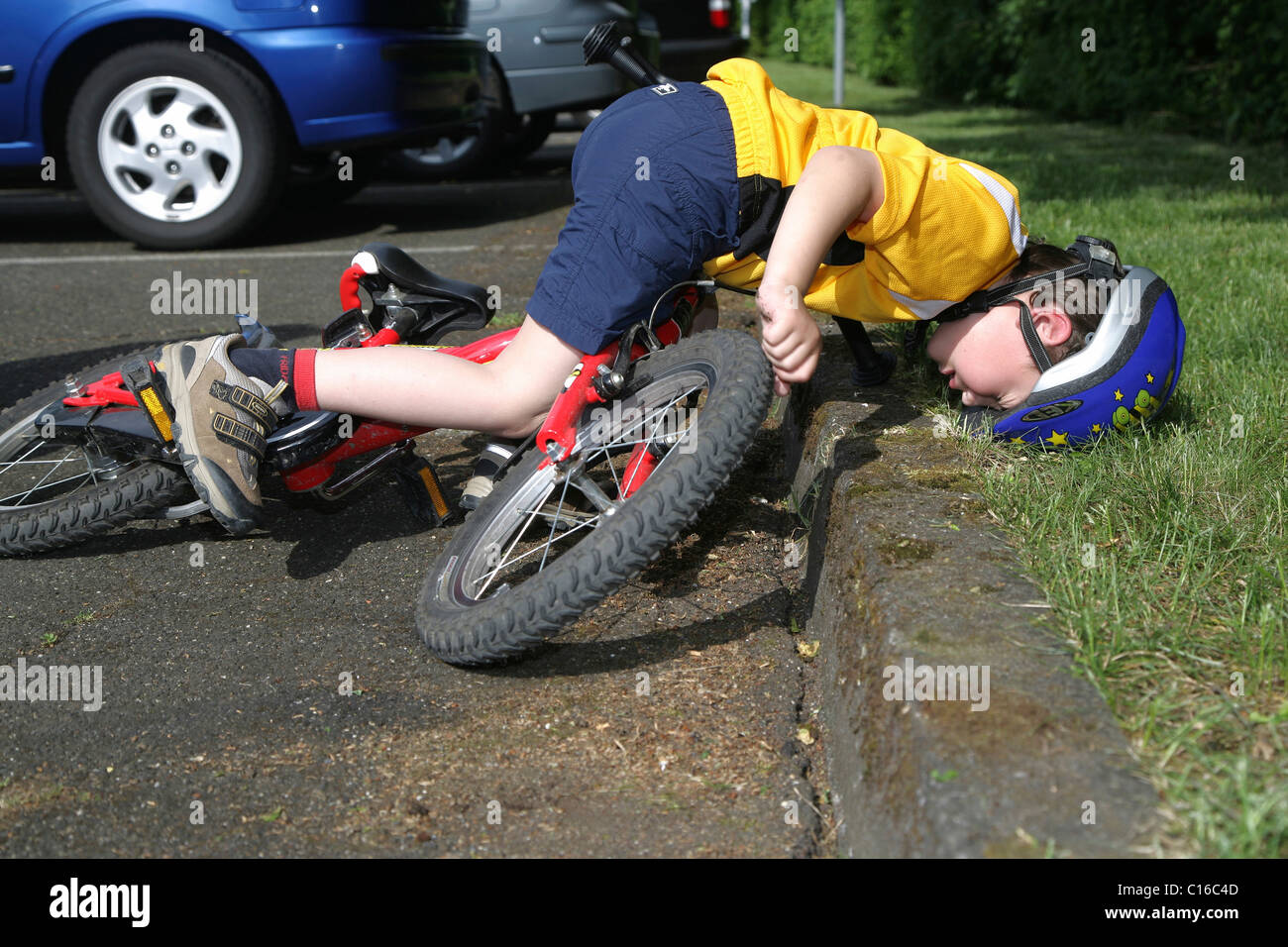 Five-Year-Old Boy das Tragen eines Helms beim Radfahren Sturz von seinem Fahrrad gestellt Foto Stockfoto