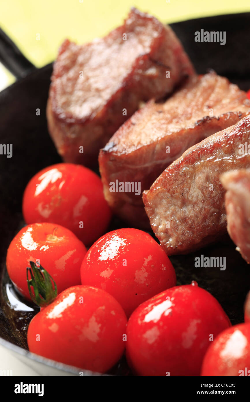 Schweinefleisch-Kebab und Cherry-Tomaten in einer Pfanne Stockfoto