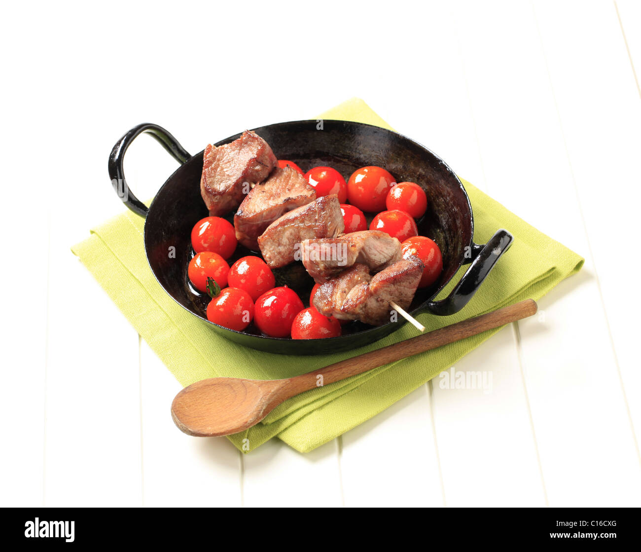 Schweinefleisch-Kebab und Cherry-Tomaten in einer Pfanne Stockfoto