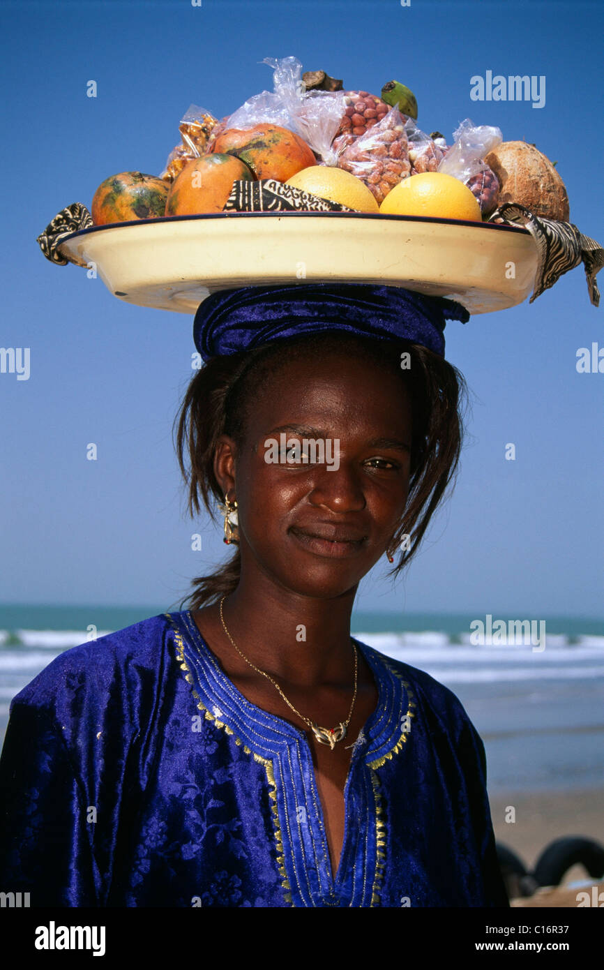 Einheimische Frau am Strand Essen auf einem Tablett tragen ausgewogen auf dem Kopf, Senegal, Afrika Stockfoto