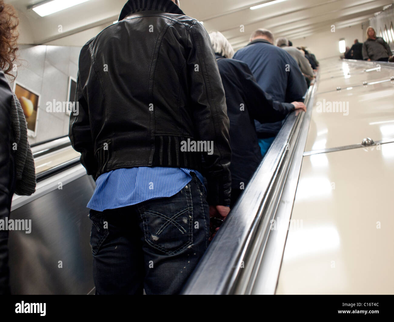 Junger Mensch gekleidet in Turnschuhen und Jeans auf einer Rolltreppe in Stockholm Schweden Stockfoto