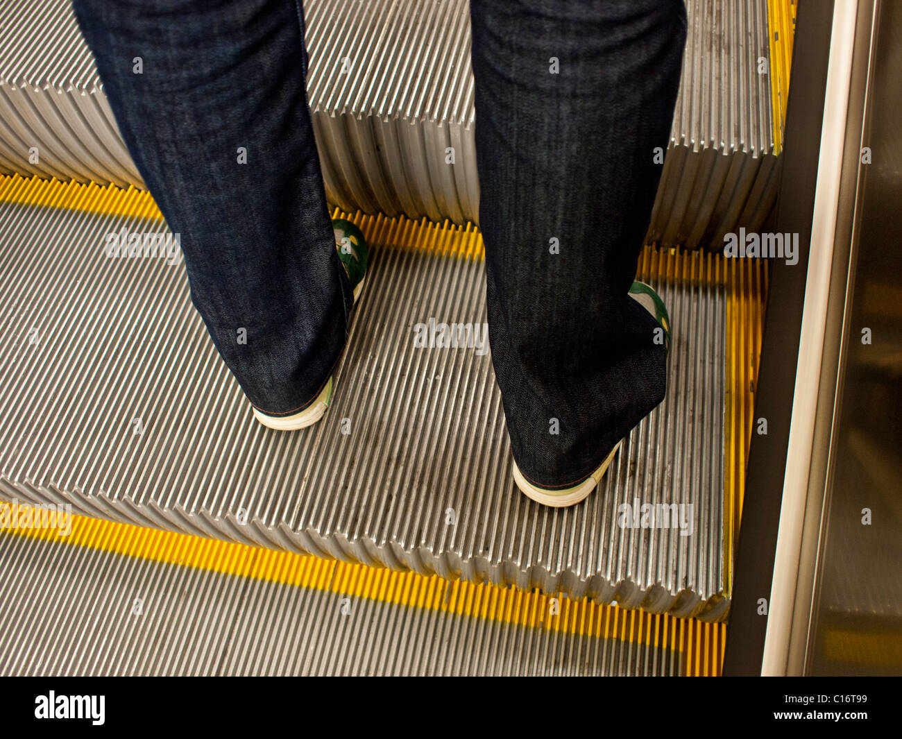 Junger Mensch gekleidet in Turnschuhen und Jeans auf einer Rolltreppe in Stockholm Schweden Stockfoto