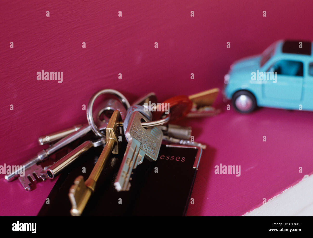 Detail der Schlüsselbund ruht auf einem Leder-Adressbuch. Ein blaues Spielzeugauto ist im Hintergrund Stockfoto