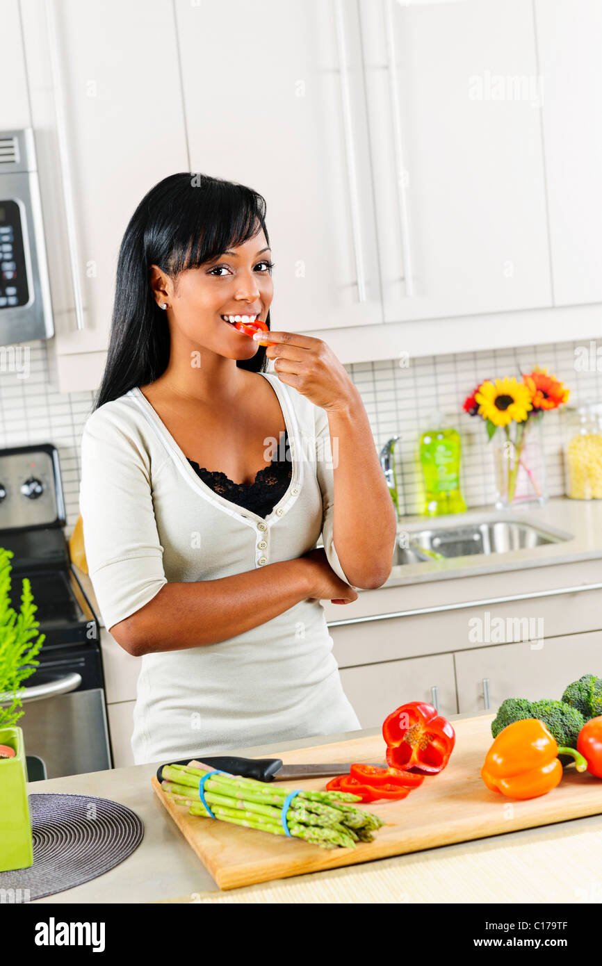 Lächelnde schwarze Frau schmeckenden Gemüse in der modernen Küche Interieur Stockfoto