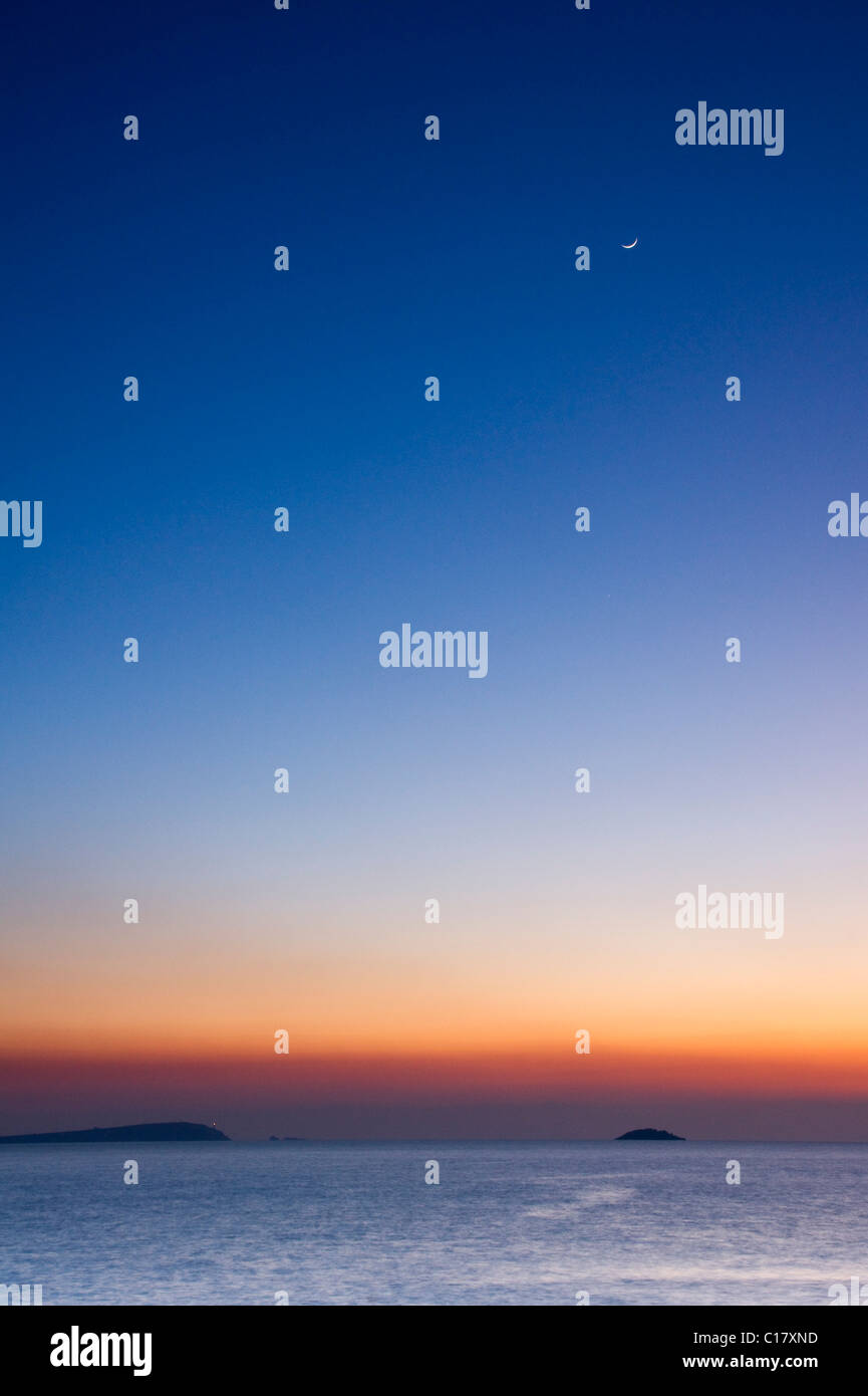 Blick auf Stepper Point und fernen Trevose Head, Cornwall nach Sonnenuntergang mit der Mond hoch oben Stockfoto