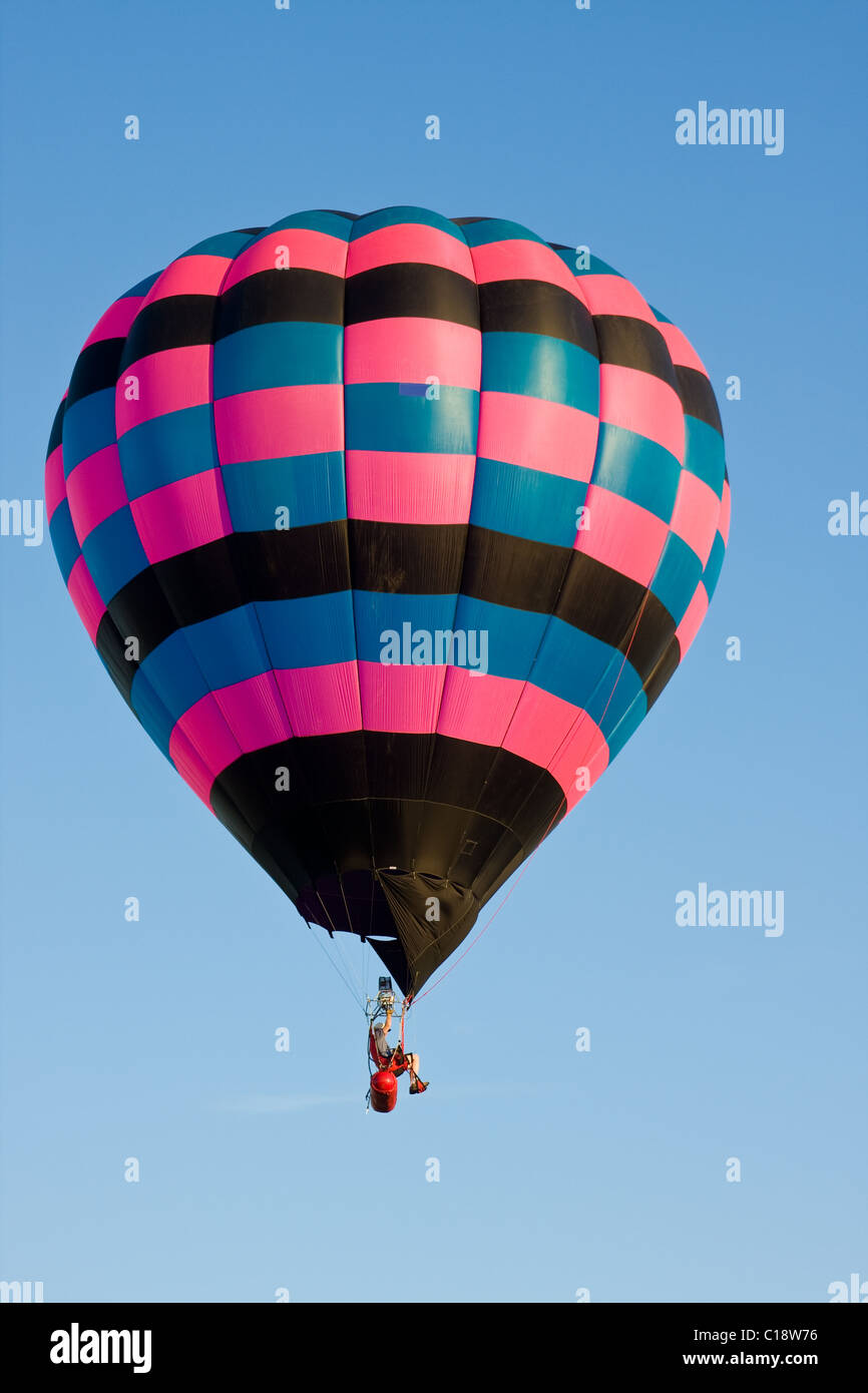 Ein bunter Heißluftballon auf einem Festival schwebt in der Luft an einem klaren Tag. Stockfoto